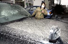 Resident washes car covered with ash from volcano